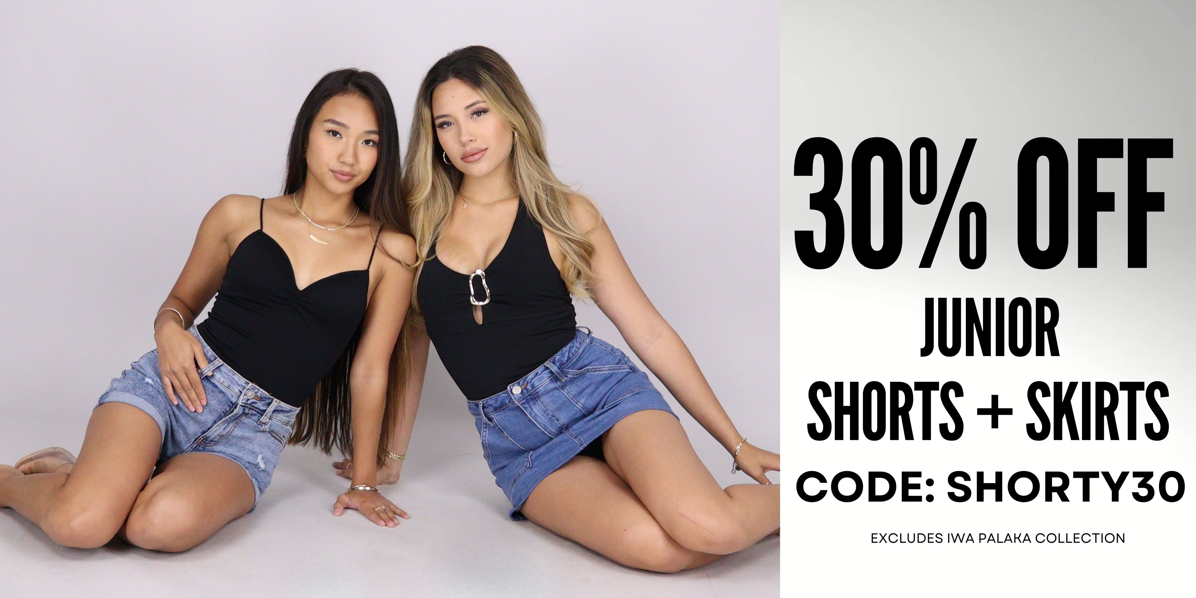 Two young women posing in matching black camisole tops and denim shorts/skirts, seated against a light gray studio background with large promotional text on the right reading '30% OFF JUNIOR SHORTS + SKIRTS CODE: SHORTY30'.