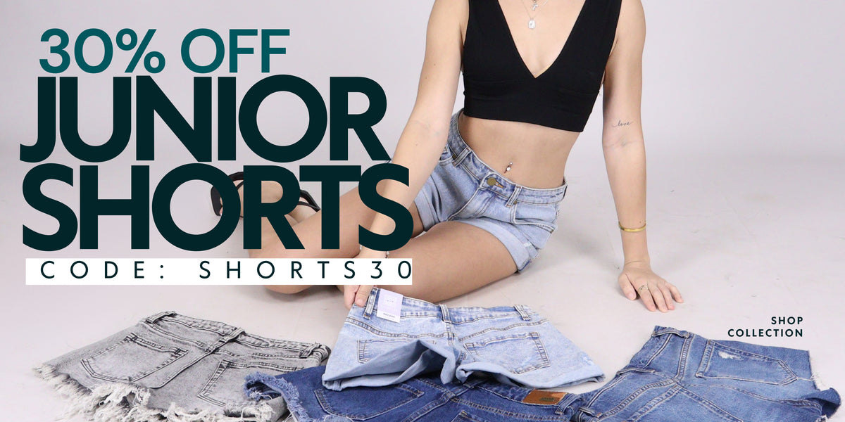 A promotional banner for 'Junior Shorts' showing a model sitting on a light gray floor surrounded by various denim shorts, with large text reading '30% OFF JUNIOR SHORTS' and a code 'CODE: SHORTS30'.