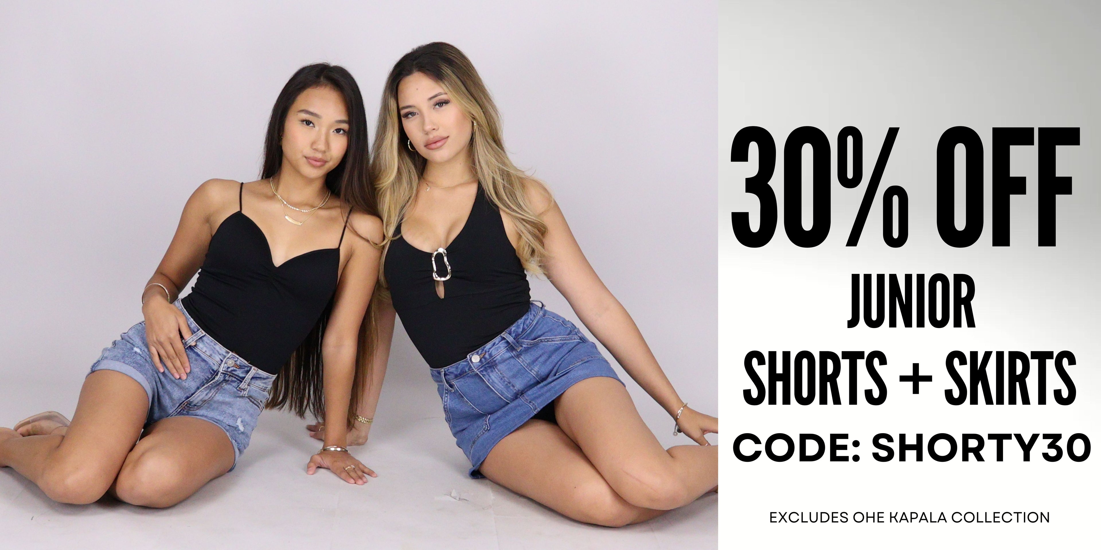 Two women sitting side by side wearing black tops and denim shorts with a promotional text overlay for 30% off junior shorts and skirts. Use Code: SHORTY30
